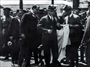1927 – İstanbul gezisinde beyaz paltosunu giymeye çalışırken. Sağında MEB Mustafa Necati Bey görülmektedir
